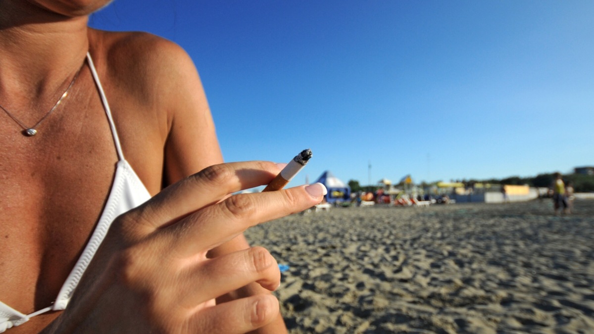Девушка с сигаретой на пляже