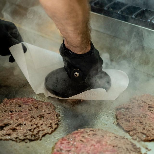 Viande écrasée sur la plaque de cuisson pour créer un smash burger chez Howard à Marseille